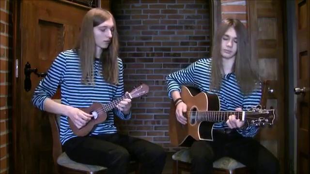 Two musicians on stage playing acoustic guitar and ukulele.